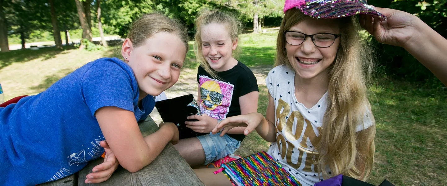 Group of smiling female campers sitting at picnic table