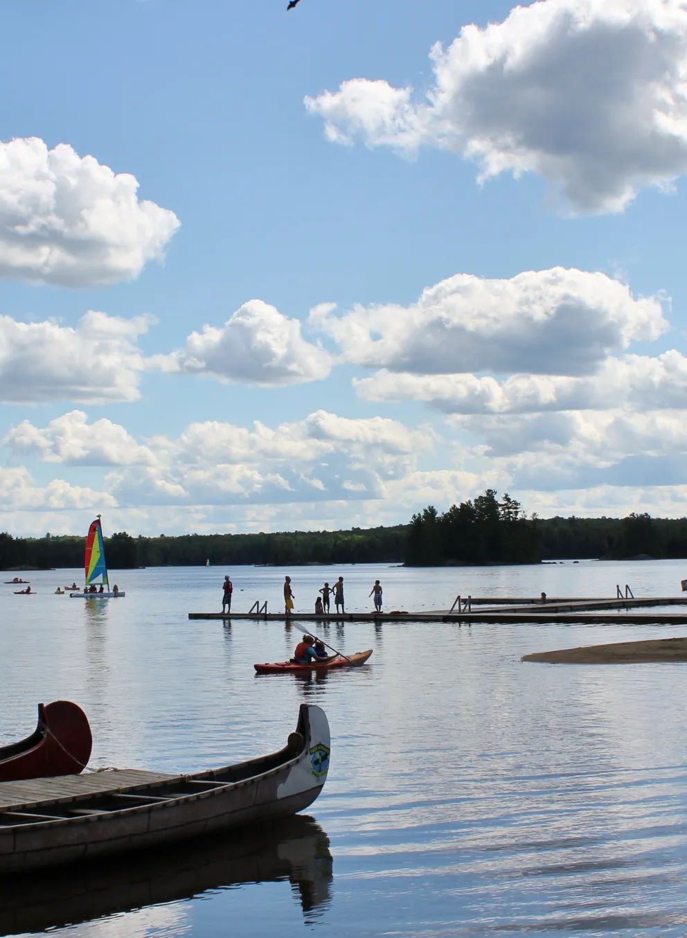Koshlong Lake waterfront with campers on the dock and wind surfing