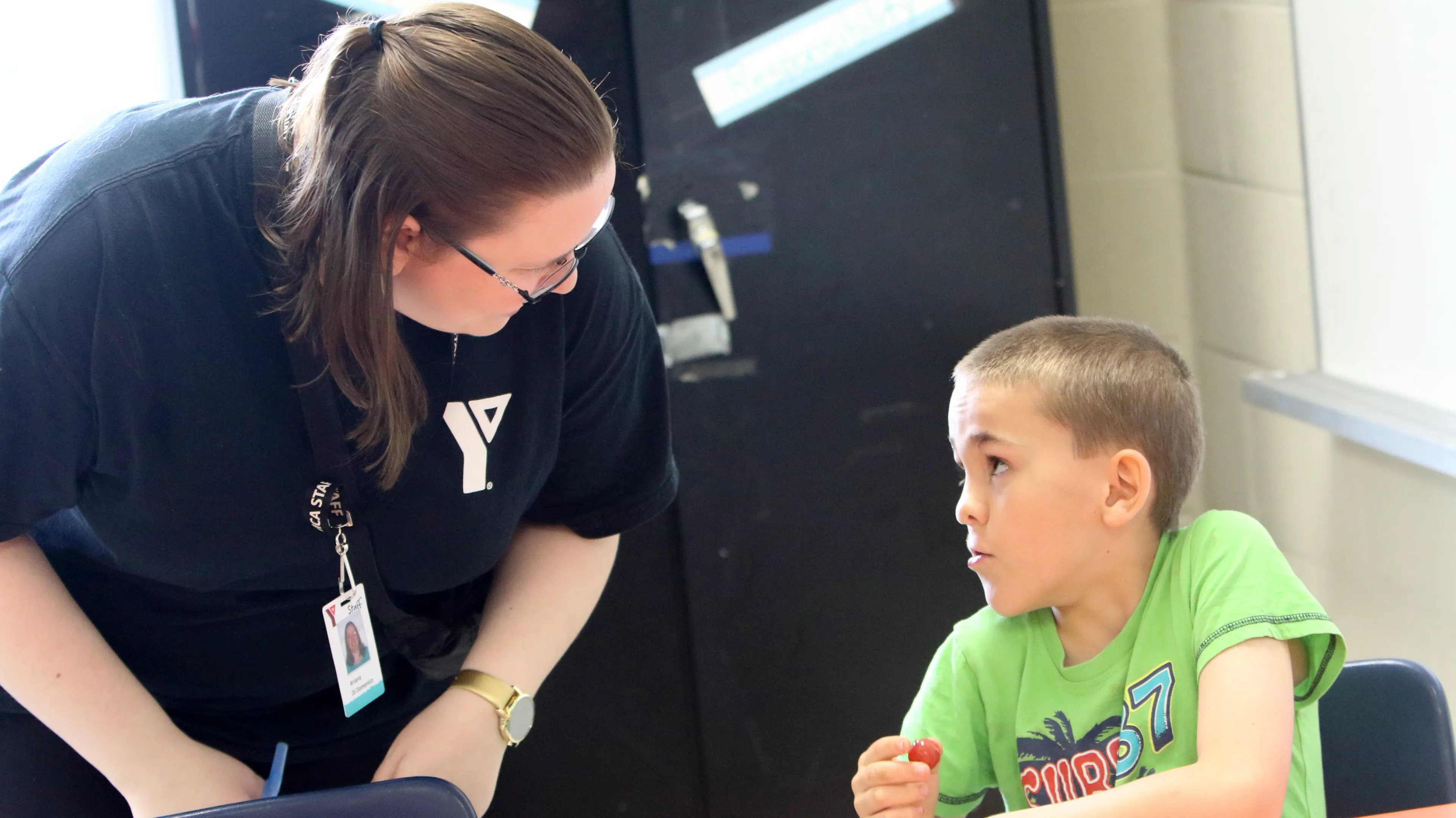 Educator bent over speaking with seated child