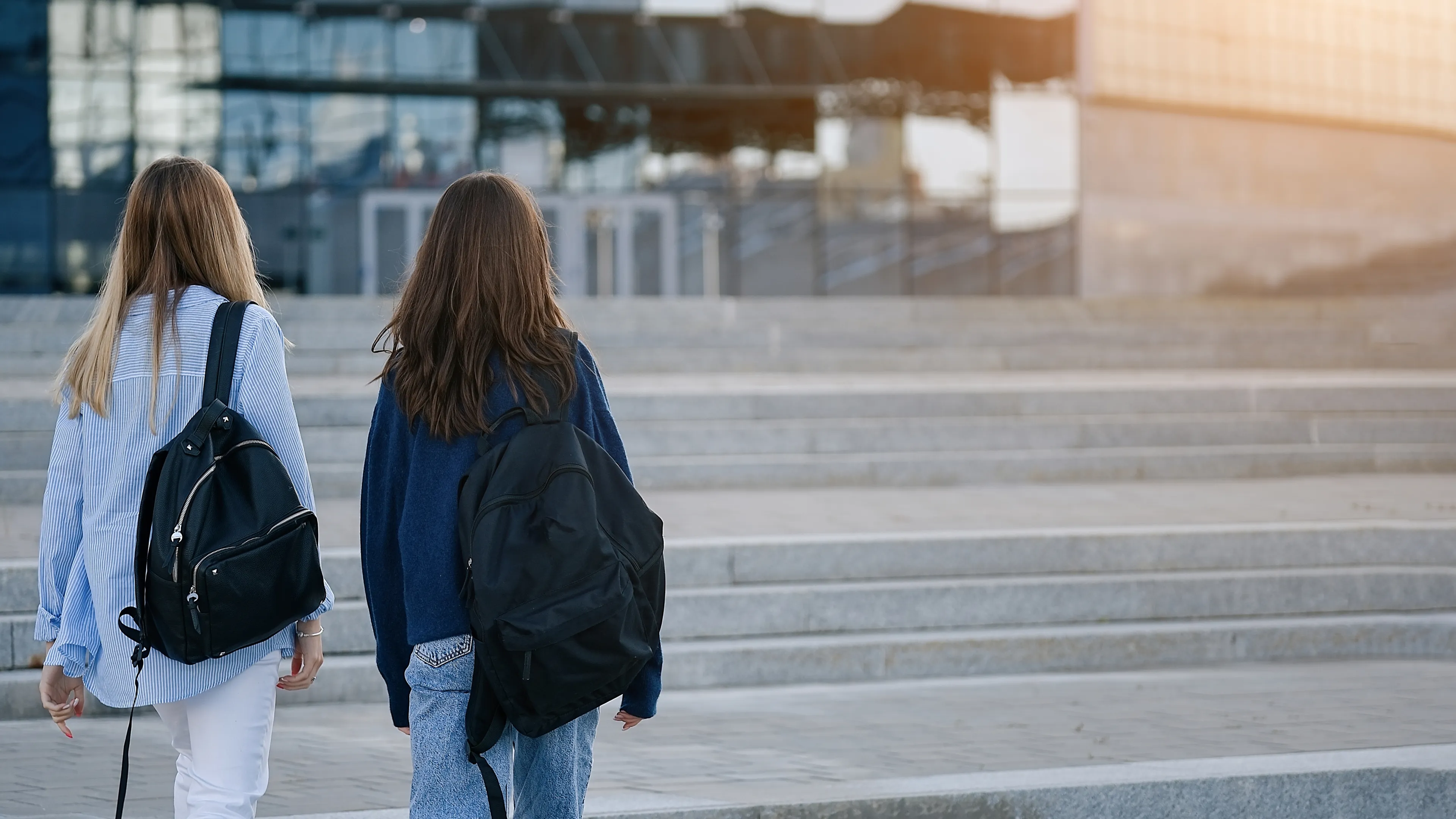 Two young people walking outside with backpacks