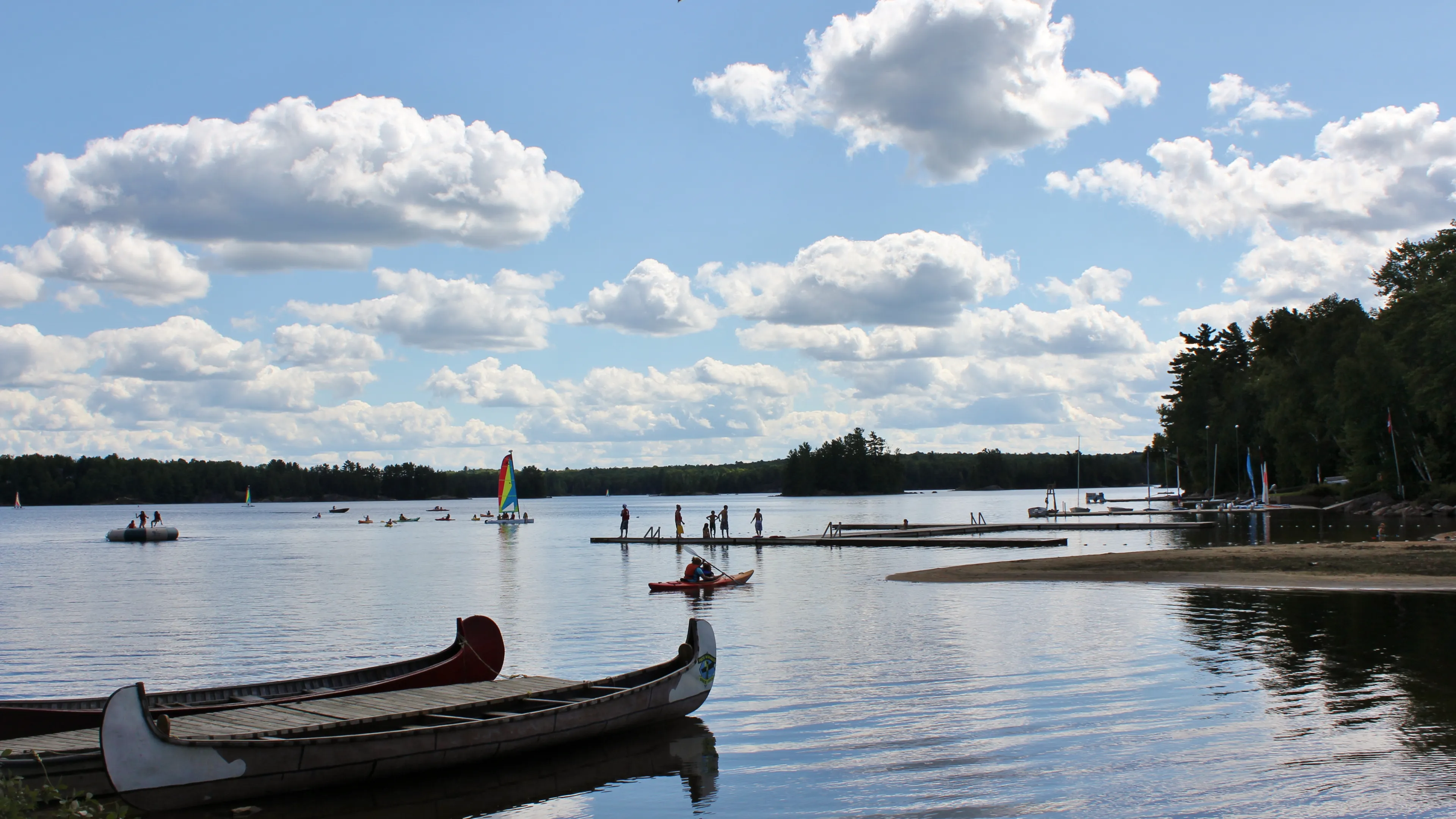 Koshlong Lake waterfront with campers on the dock and wind surfing