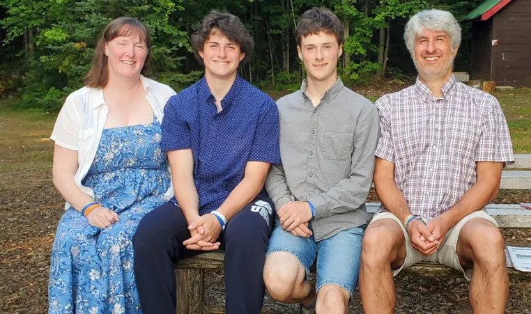 family sits on picnic bench smiling