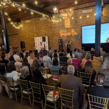 dozens of people sit and watch a presentation by the YMCA