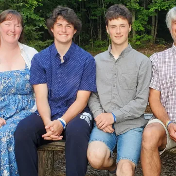 family sits on picnic bench smiling