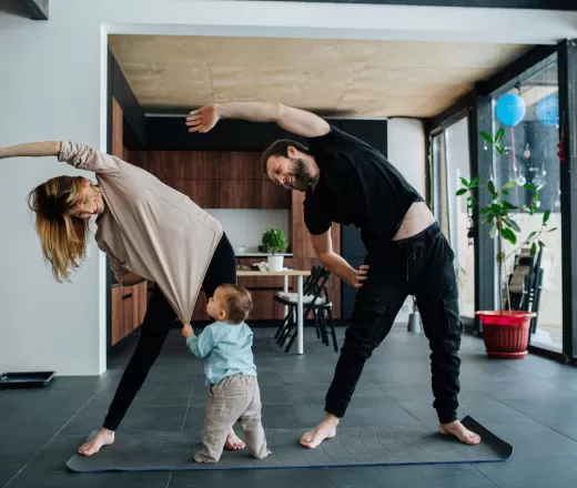 Parents with toddler exercising in home on yoga mat