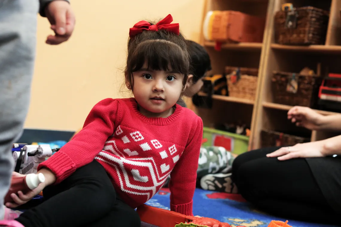 Female preschool child in red sweater playing on a floor mat