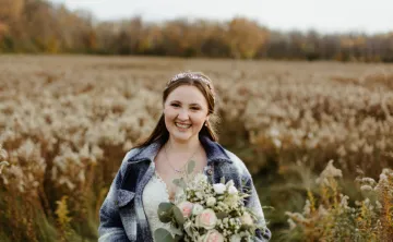 bride in field wearing blue flannel